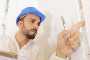 A young man inspects the drywall in a home